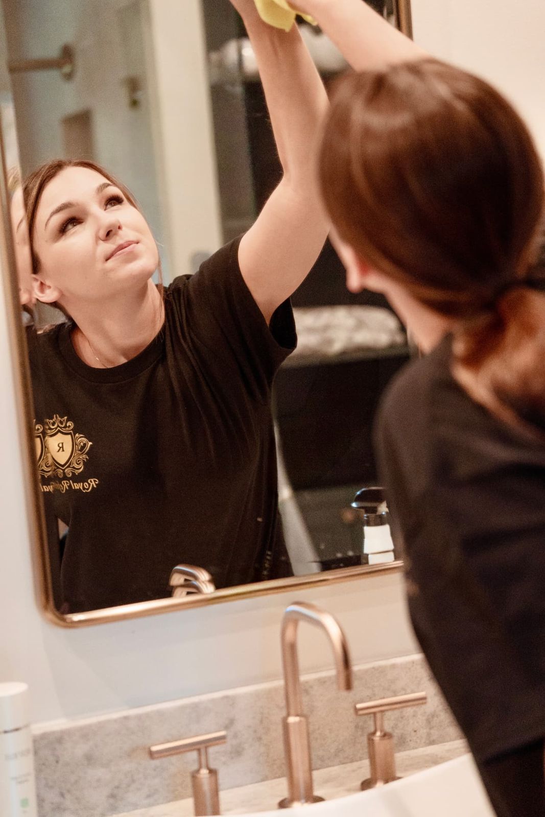 Cleaner polishing a bathroom mirror